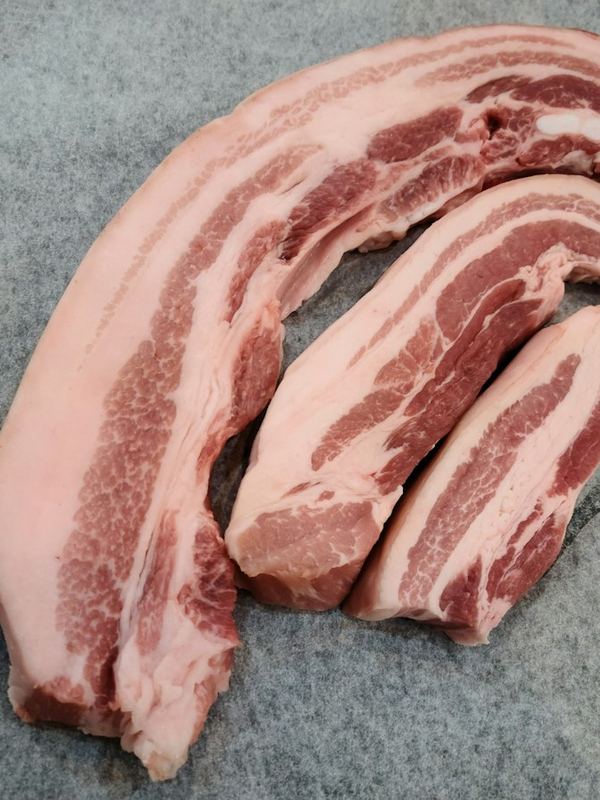 Tiras de barriga de porco crua sobre pedra